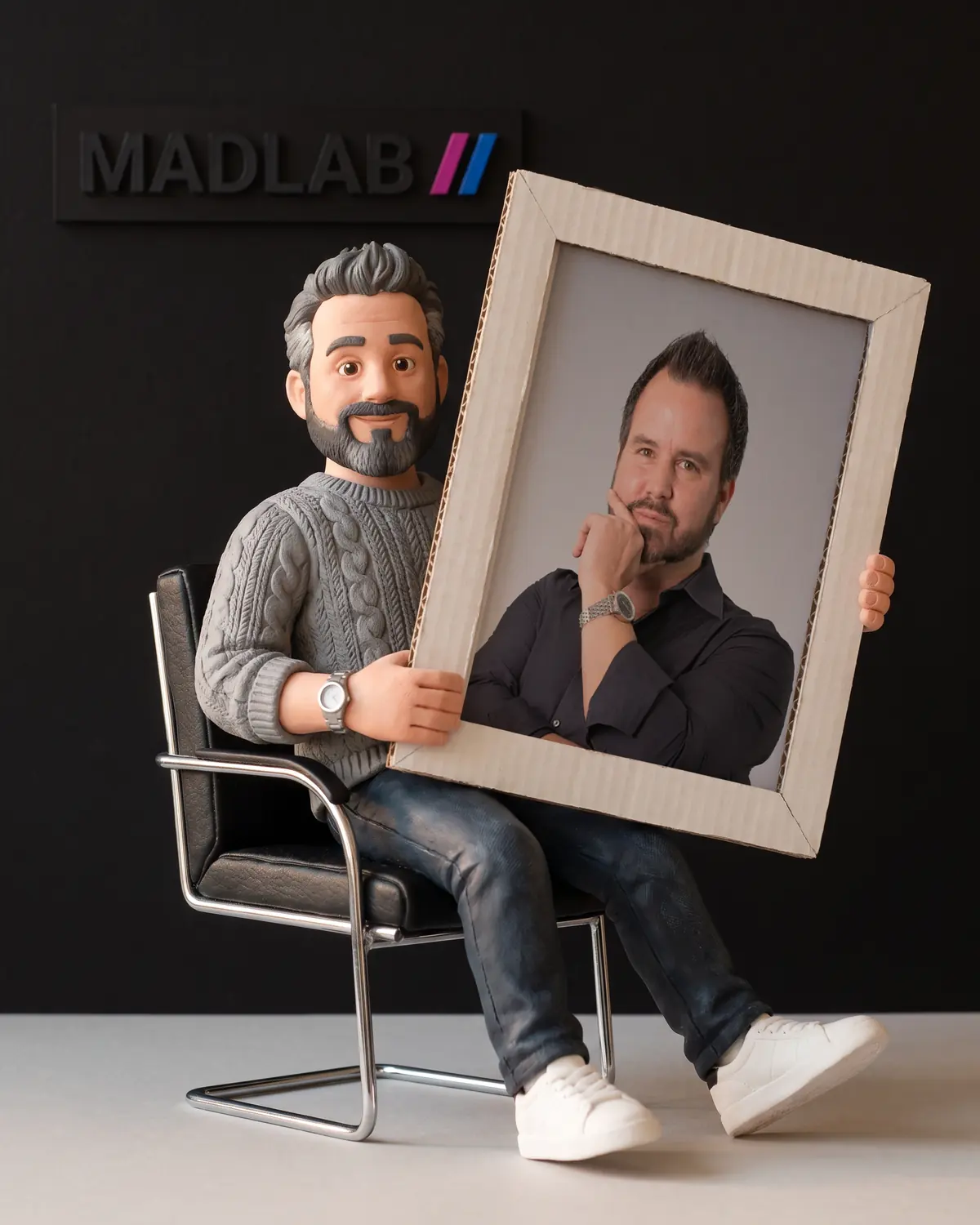 Knetfigur von Matthias auf einem schwarzen Bürostuhl, mit einem Kartonrahmen und einem Foto des echten Matthias